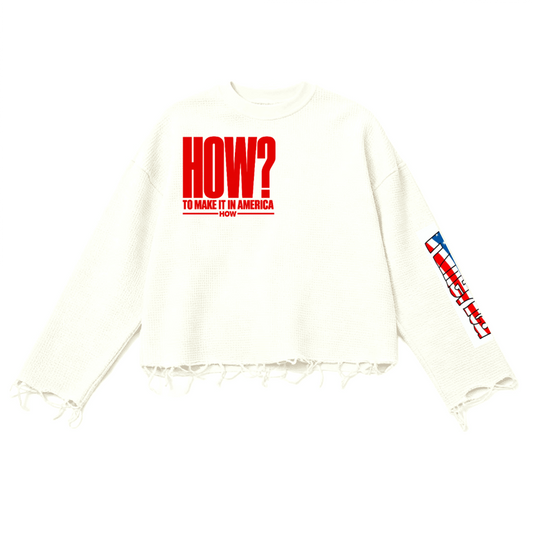 An off-white cropped long-sleeve sweatshirt with a distressed frayed hem, featuring a bold red graphic on the chest that reads 'HOW? TO MAKE IT IN AMERICA' and a matching red, white, and blue graphic on the right sleeve.
